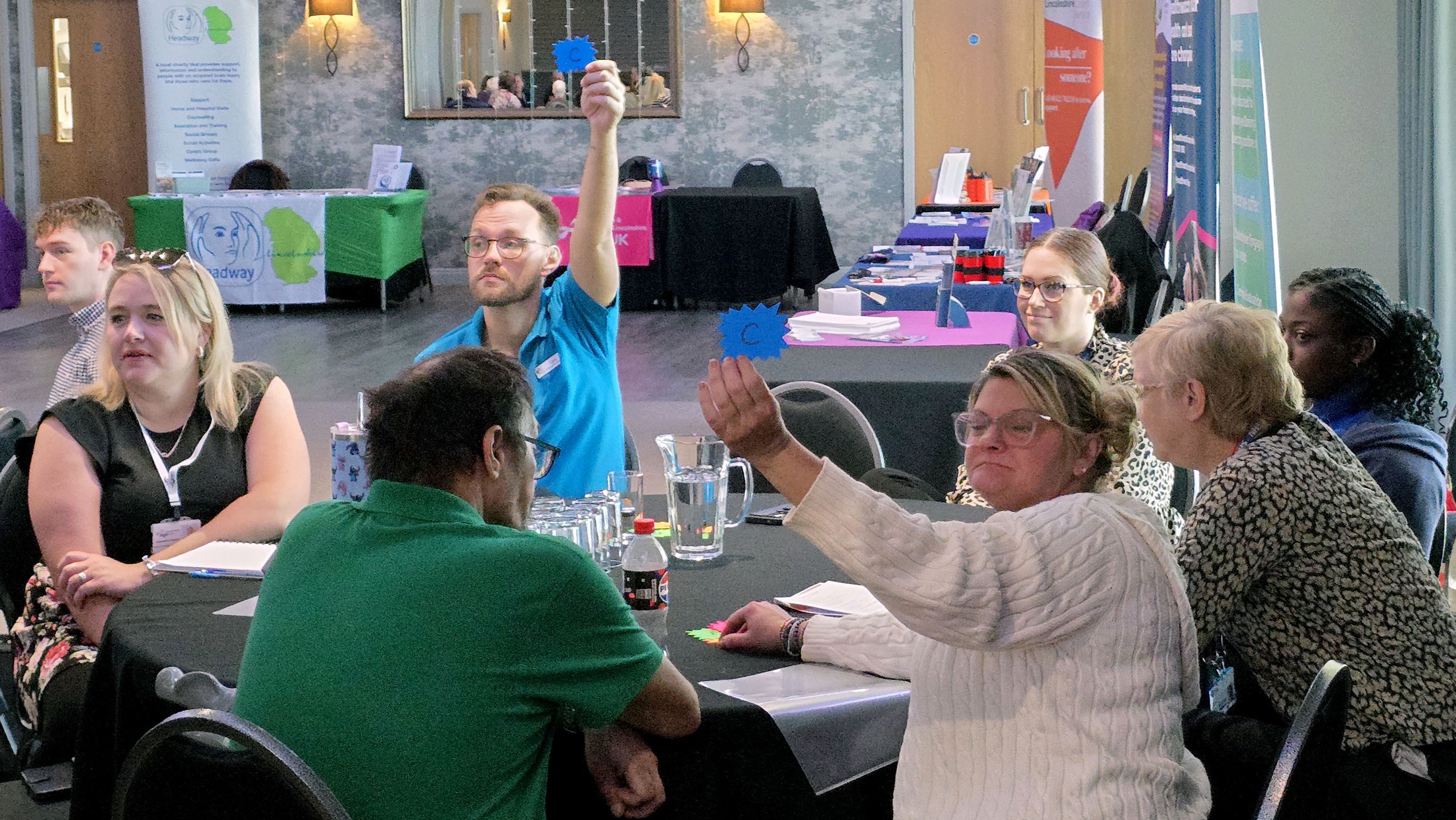 a group of people on a table, one holds up a cardboard letter
