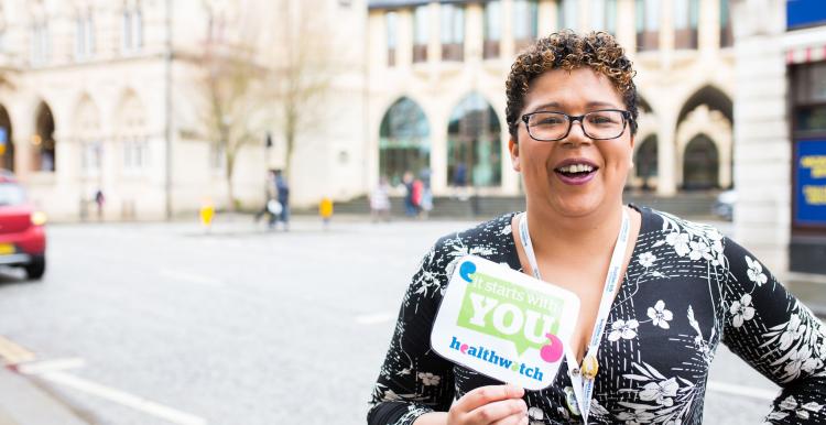 Healthwatch staff member holding an It Starts With You sign to promote the campain Healthwatch staff member holding an It Starts With You sign to promote the campain