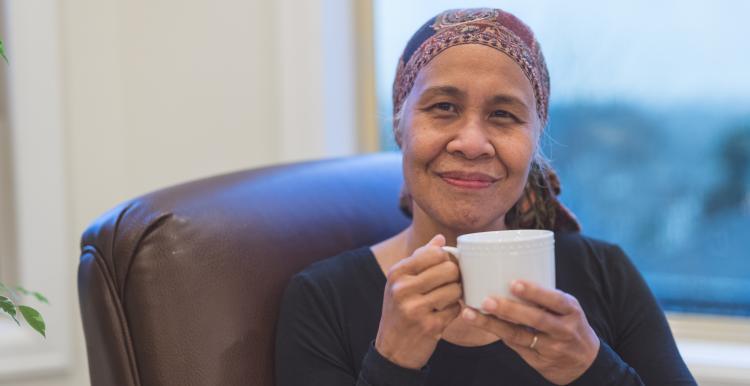 Vinny cancer patient sat drinking tea smiling to camera