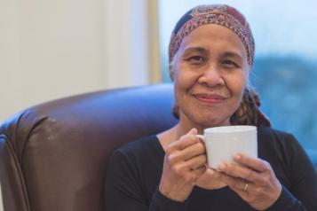 Vinny cancer patient sat drinking tea smiling to camera 