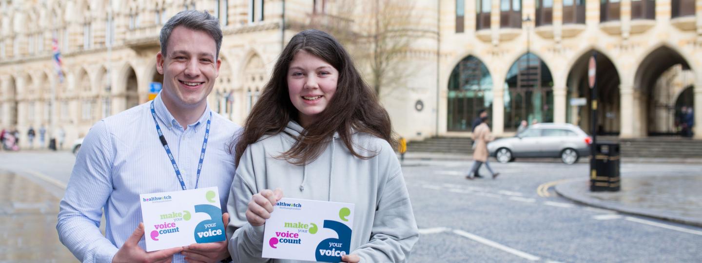 Young adult male volunteer with young female volunteer holding promotional material